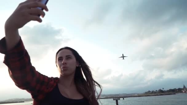 Hermosa chica toma una selfie con el avión en el teléfono. Blogger chica de viajes — Vídeos de Stock