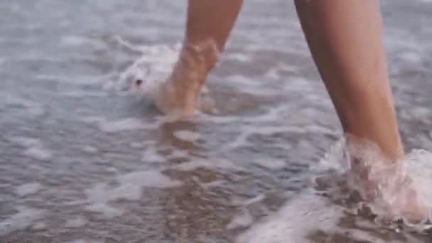 Dívčí nohy a nohy při chůzi po vodních vlnách štíhlé ženské nohy se pohybují po nábřeží šplouchání vody dovolená na pláži v pomalém pohybu dokonalá Ženská noha s radostnou chůzí na pobřeží Užijte si letní prázdniny. — Stock video