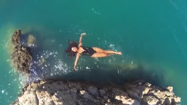 Vista aérea de la hermosa chica en bikini, flotando en un agua de mar cristalina y azul — Vídeo de stock