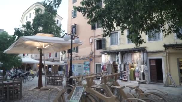 Griekenland. Corfu. 2019. moderne hout geparkeerd fietsen te huur op racks op Urban City Street. — Stockvideo