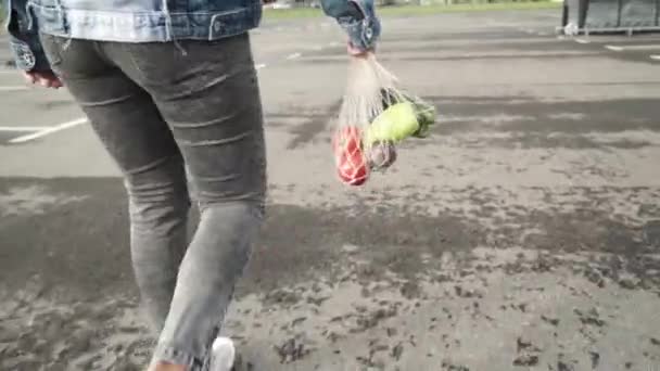 Kız sebze ile yeniden mesh dize örme alışveriş çantası tutar. Sağlıklı gıda kavramı — Stok video