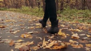 Autumn Park 'ta sarı yapraklı bir çocuğun ayaklarının yakın çekimi. Bir kız ormandaki sarı yaprakların arasından geçer..