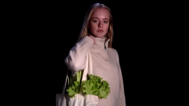 Sıfır atık ve ekolojik torba. Eko-alışveriş. Kızın siyah arka planda meyve ve sebzeli yeniden kullanılabilir market poşetleri var. — Stok video