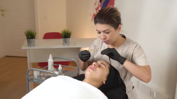 A Beautiful Girl in a Beauty Salon Does a Lamination Lashes. Beautician Performs the Procedure Eyelash Fragmentation. Beautician master — Stock Video