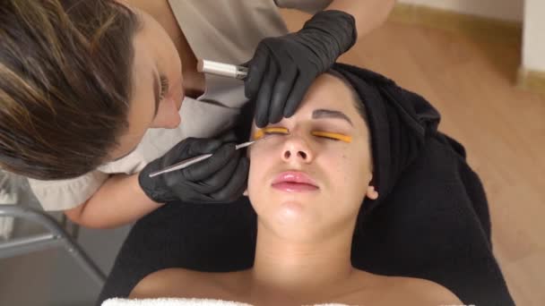 Uma linda garota em um salão de beleza faz um cílios de laminação. Esteticista Executa o Procedimento Fragmentação das Cílios. Fechar — Vídeo de Stock