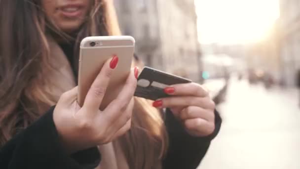 Student på gatan med kreditkort och telefon Brunett kvinna online betalningar via Internet från bankkort på smartphone. Nätbutikskoncept. Närbild — Stockvideo