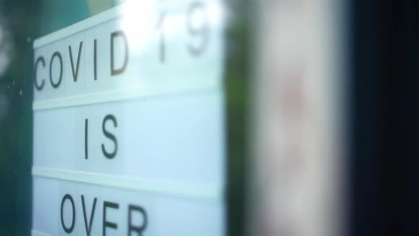 Lightbox con como signo COVID-19 ESTÁ SOBRE estamos abiertos de nuevo detrás de una puerta de cristal de la cafetería. La cuarentena terminó con un concepto . — Vídeos de Stock