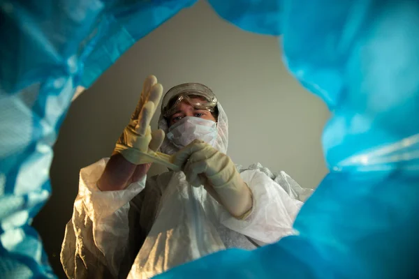 Fin de la victoria de cuarentena sobre el coronavirus. Vista desde el bote de basura un médico hombre se quita una máscara médica y guantes de látex y los tira. Papelera con equipo de protección personal desechable Imagen De Stock