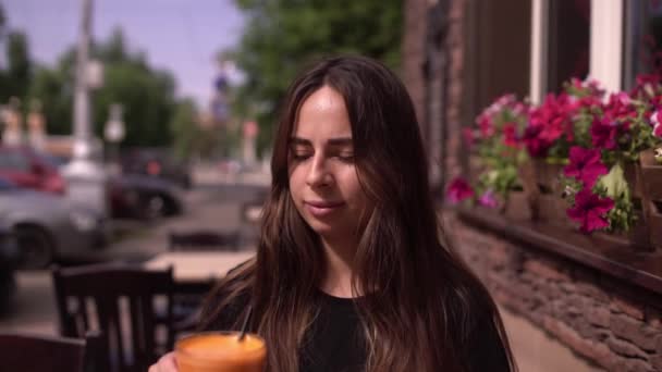 Mujer bebiendo jugo fresco de zanahoria en un café callejero día de verano — Vídeos de Stock