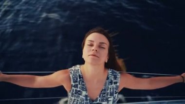 Yelkenli teknede poz veren güzel bir esmerin portresi, gemi seyahatindeki seksi bir kadının yakın plan portresi. Seyahat, yansıma ve rahatlama kavramı.