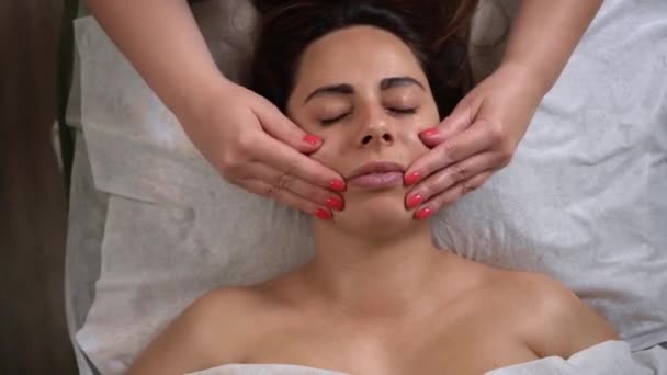Spa masaj facial. Procesul de masaj facial sculptat în biroul cosmetologului. O femeie frumoasă are grijă de aspectul ei. Beautician masează clientul ei, elimină semnele de îmbătrânire din — Videoclip de stoc