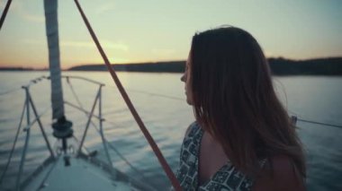Yolcu gemisi yolcusu okyanusun üzerinde gün batımını seyrediyor dışarıda tatilin tadını çıkarıyor. Zarif genç bayan teknede maceranın tadını çıkarıyor..