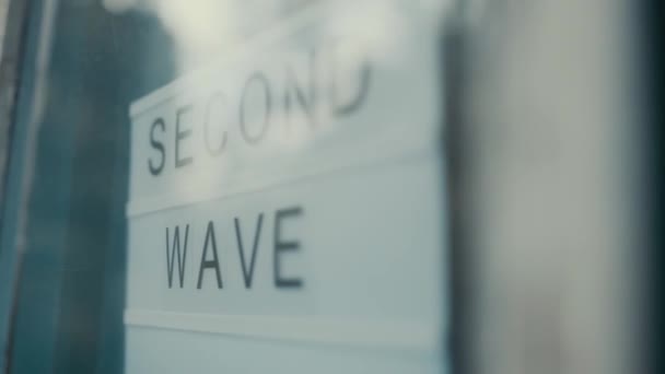 Lightbox con come segno Second Wave dietro una porta a vetri dell'hotel. Il concetto di quarantena della seconda ondata. — Video Stock