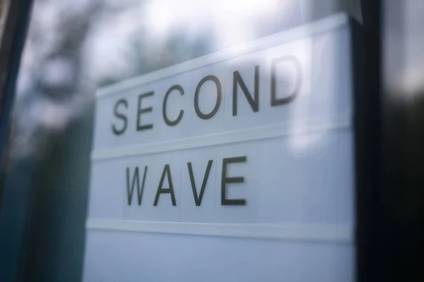 Lightbox s nápisem Second Wave za skleněnými dveřmi hotelu. Koncept karantény druhé vlny. — Stock fotografie