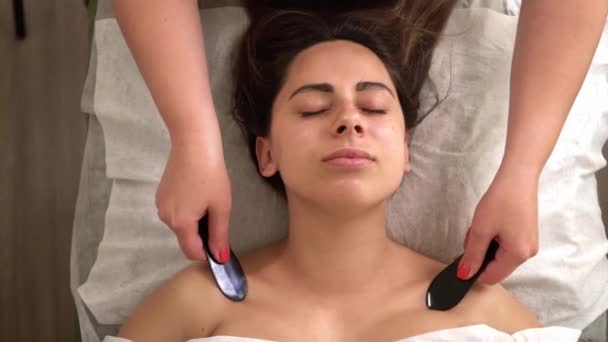 Spa masaj facial. Procesul de masaj de sân sculptate biroul cosmetologului. O femeie frumoasă are grijă de aspectul ei. Beautician masaje cu guasha clientul ei, elimină semnele de îmbătrânire — Videoclip de stoc