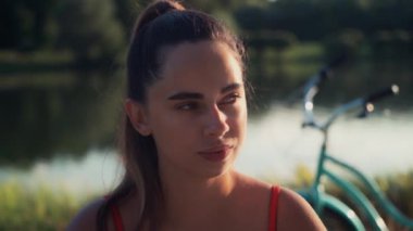 Gün batımında kadınların yüzünü kapatın, güzel yeşil gözler, portre, açık hava, güneş ışığı, ağır çekim. Arka plan bisikleti. Sağlıklı yaşam tarzını kabul et