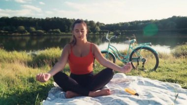 Namaste Mudra poziyonunda ellerini nilüfer çiçeğinin arka planında oturarak meditasyon yapan kadın. Kadın, doğada yalnız başına yoga yapıyor. Sağlıklı yaşam tarzını kabul et