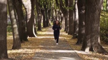 Parkta koşan kadın koşucu spora gider. Koşucu atlet kız doğayla iç içe koşuyor. Yeşil Park 'ta sabah koşusu yapan bir kadın. Sağlıklı insanlar parkın aktif konseptini kullanır. Günbatımı yaşam tarzı siluetini çalıştıran kız