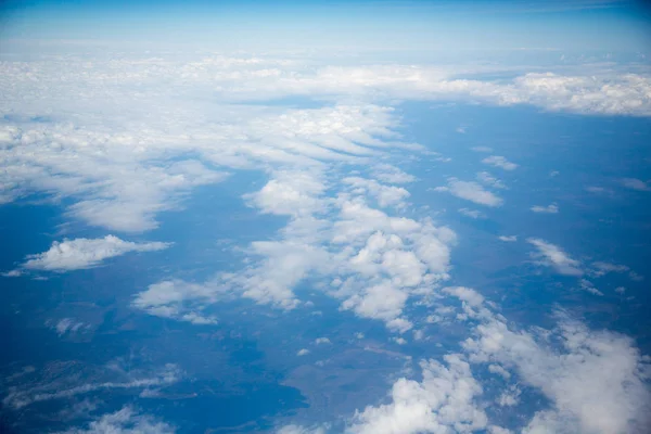 Nubes y cielo visto a través de la ventana de un avión — Foto de Stock