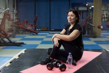 Spor salonunda pembe yoga mat oturan kıdemli kadın. Close. Kopyalama alanı.