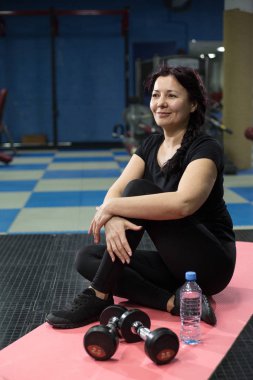 Spor salonunda pembe yoga mat oturan kıdemli kadın. Close. Kopyalama alanı.