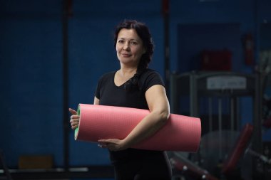 Spor salonunda pembe yoga mat tutan kıdemli kadın. Close. Kopyalama alanı.