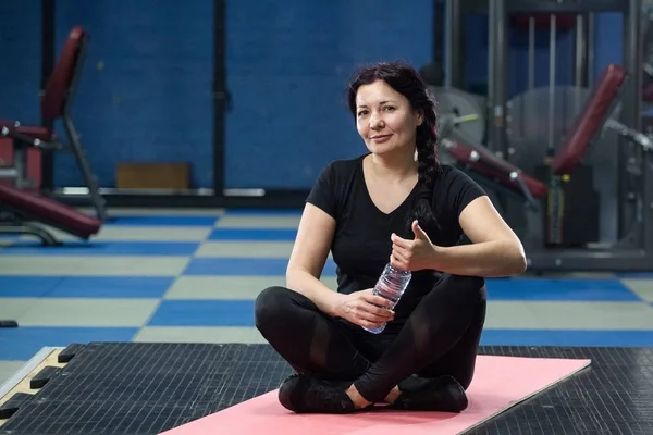 Spor salonunda pembe yoga mat oturan kıdemli kadın. Close. Kopyalama alanı.