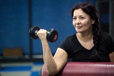 Spor salonunda yaşlı kadın, dumbbells ile çalışıyor. Close. Kopyalama alanı.