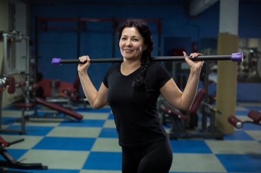 Kıdemli kadın omuzlarında bir vücut Bar ile spor salonunda duruyor. Close. Kopyalama alanı.