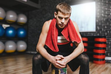 Sporcu rahatlatıcı egzersizler boyun salonunda kırmızı havlu ile sonra. Metin veya reklam için kopya alanı ile ağırlık terbiye ile sert çalışmadan sonra çekici atletik erkek geri kalan.