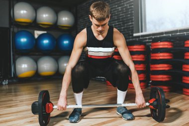 Güçlü genç beyaz vücut geliştirmeci egzersiz halter salonunda ile. Kas fitness adam hazırlanılıyor modern fitness Club başının üstünde bir halter uygular. Fonksiyonel eğitim. Sağlıklı yaşam tarzı