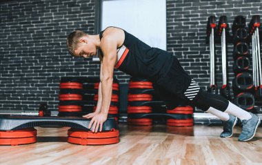Sportif atlet eğitmen adam Step Aerobik fitness Club itmek yapıyor. Yakışıklı erkek göğsüne Step modern spor salonunda egzersiz olduğunu. Spor, yaşam tarzı ve insanlar kavramı.
