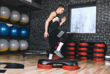 Sağlık fitness kulübü atlar kadar adım yapan sportif atlet erkek tarafı tam vücut görünümü. Yakışıklı erkek bacaklarına Step modern spor salonunda egzersiz olduğunu. Spor, yaşam tarzı ve insanlar kavramı.