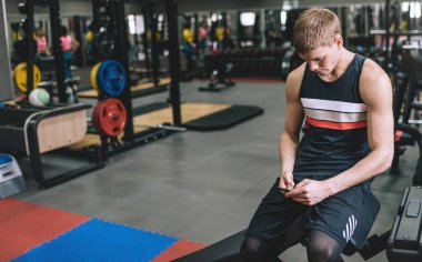 Internet üzerinden sosyal medya sörf onun akıllı telefon kullanan fitness egzersiz sonrası istirahat Beyaz atletik adam. Sportif erkek bir brench metin veya reklam için kopya alanı ile spor salonunda oturan.