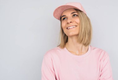 Güzel pembe elbise ve şapka, beyaz dişler sarışın kadın ile çekici görünüm ile gülümseyen bir portre Studio beyaz duvara poz. Mutlu kadın gösteren olumlu duygu.