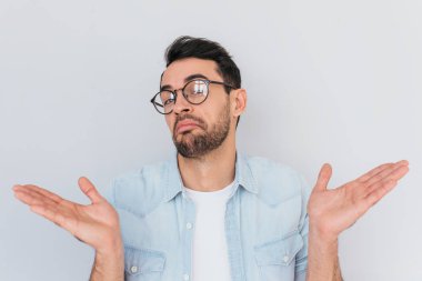 Beyaz emin erkek jestleri şüpheyle kopya alanı ile el ile yapmak. Belirsiz genç şık anız erkek moda yuvarlak gözlük ile demin mavi gömlek giyer, şaşkın şaşkın, omuz silkiyor omuz