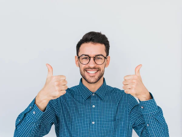 Sağlıklı dişlek sağlıklı gülümseme, yakışıklı erkek ile her iki el başparmak gösterilmesini kameraya mutlu ifade ile seyir yuvarlak trendy gözlük, mavi gömlek giyer. Beden dili, duygu kavramı