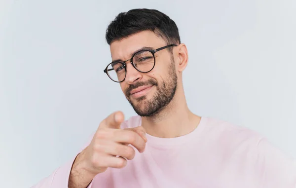 工作室的肖像 高兴的男性穿着粉红色的毛衣 指向你 选择某人或广告产品 英俊的微笑的人显示在照相机 隔绝在白色墙壁背景 — 图库照片