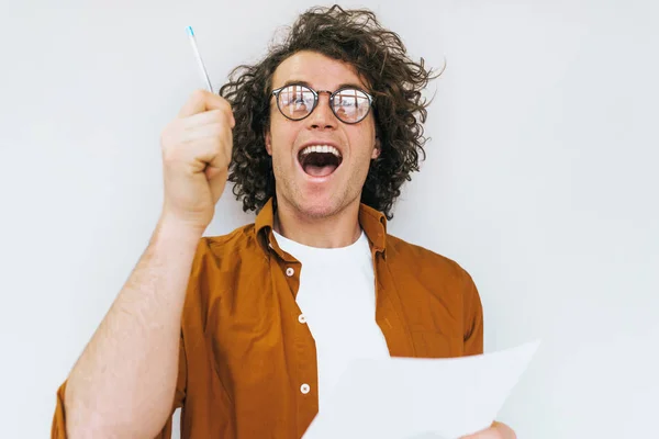 ホワイト スタジオの壁を越えてポーズの試験紙新しいチェックリストの巻き毛を持つ幸せな陽気な学生の肖像画を書き込みます ノートブックで丸いメガネはノートを着て成功した労働者の男の笑みを浮かべて — ストック写真
