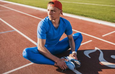 Beyaz atlet koşu parkuru üzerinde oturan germe egzersizleri yapıyor. Birlikte kaçmak için hazırlanıyor ya da egzersiz yaptıktan sonra rahatlatıcı katıldı ayaklı koşu parkuru üzerinde oturan runner adam. Spor ve insanlar