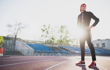 Atletik erkek stadyumda yolda poz. Çekici runner çalışan ve açık koşu için hazırlanıyor. Spor, insanlar ve yaşam tarzı kavramı.