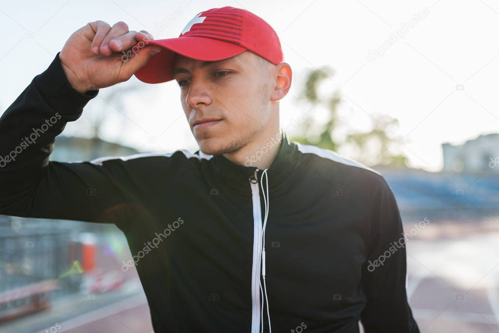 Sport, people. Portrait of sporty young male on a walkway in stadium, getting ready for his run. Focused athlete man preparing for his running workout outdoors with copy space for advertising.