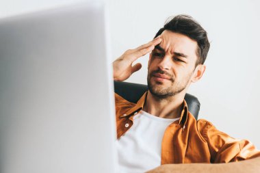 Beyaz delikanlı rahat kıyafetler içinde bilgisayar arkasında baş ağrısı var. Hayal kırıklığına uğramış genç yakışıklı adam işinde sorunlar hakkında endişeli. Uzun web konuşmadan sonra işadamı vurguladı.