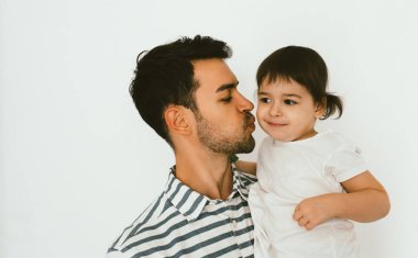 Yakın çekim yakışıklı baba portresi küçük kızı öp. Genç baba çocuğunu sarılma. Çekici bir adam küçük yürümeye başlayan çocuk kızla oynamak. Mutlu baba ve kızı. Yaşam tarzı aile.