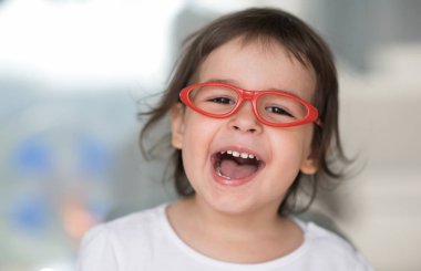Akıllı mutlu beyaz sevimli küçük öğrenci kız gülerek yakın çekim yatay portresi. Meraklı mutlu güzel bebek kız kırmızı gözlük takıyorum. Eğitim kavramı.
