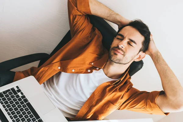 Top view of young European man in casual clothes. Frustrated young handsome man have headache while sitting at his work place with laptop pc.