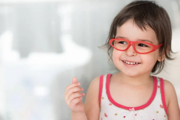 笑みを浮かべてスマートの幸せな白人かわいい小さな学生女の子の屋内の肖像画 好奇心の幸せな美しい幼児の女の子が赤いメガネを身に着けています 教育コンセプト — ストック写真