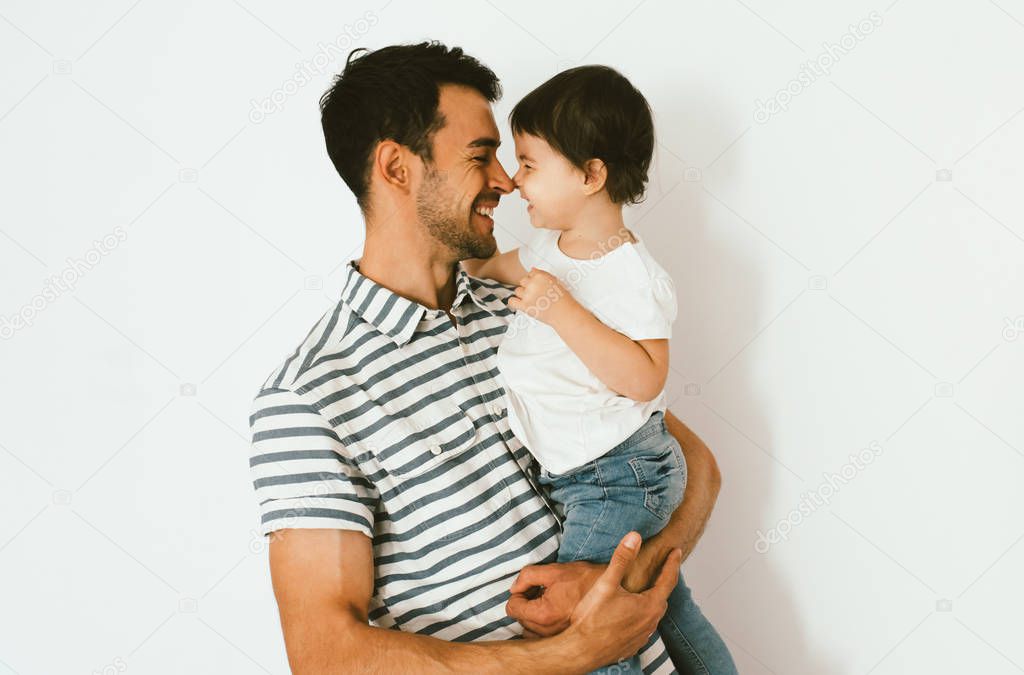Portrait of happy dad and daughter play and cuddle together against white background. Good relationship of parent and child. Happy family moments of father and toddler girl. Childhood and parenthood.