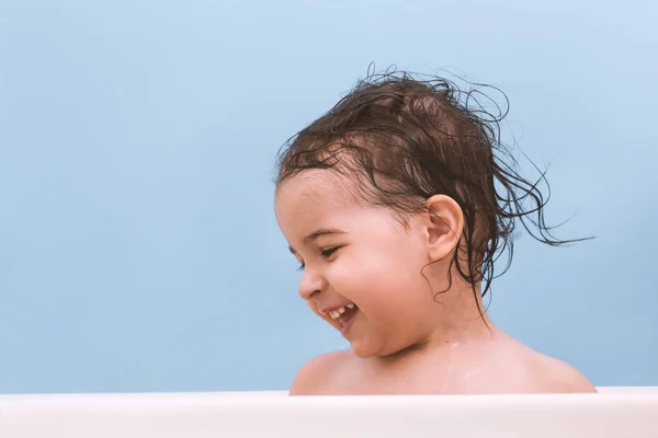 陽気な幸せな幼児赤ちゃんお風呂に泡で遊ぶ バスタブで 幼い子供 青の背景に浴室で子供を笑っています 幼児が洗濯 ヘルスケア — ストック写真