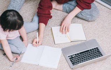 Anne ve onu genel gider görünümünü kırpılmış mi merak kızısın birlikte evde bir yerde çalışma ve bir dizüstü bilgisayar kullanarak ve kağıt üzerinde yazılı. İş kadını evde çocuk ile çalışma.